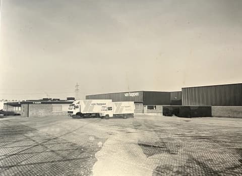 Het bedrijfspand aan de Industrieweg 74-76 in Waalwijk met twee vrachtwagens van Van Happen.